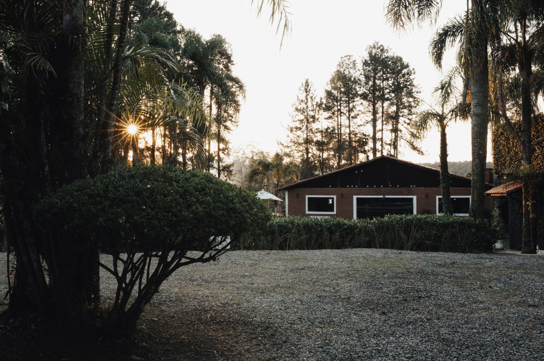 A gravel forecourt in front of a low house at dusk