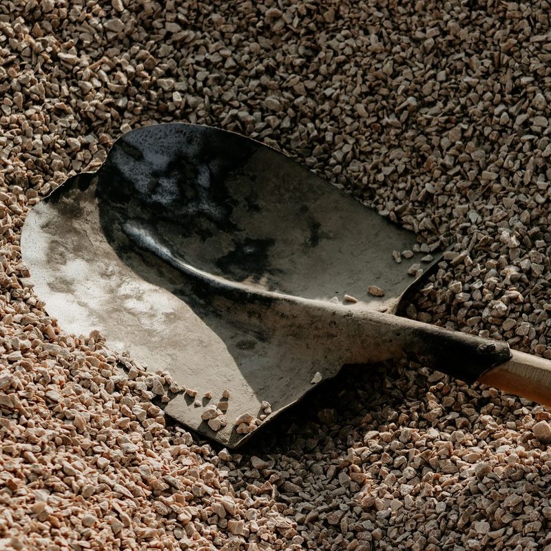 A shovel standing in a heap of crushed stone