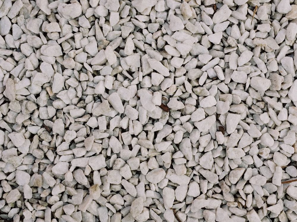 A close-up of pale grey crushed drain rock