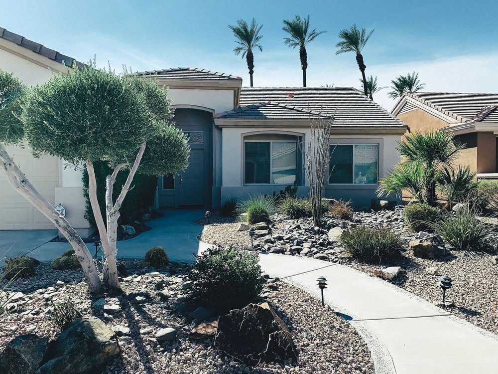 A desert home with a rock and cactus front yard under palm trees