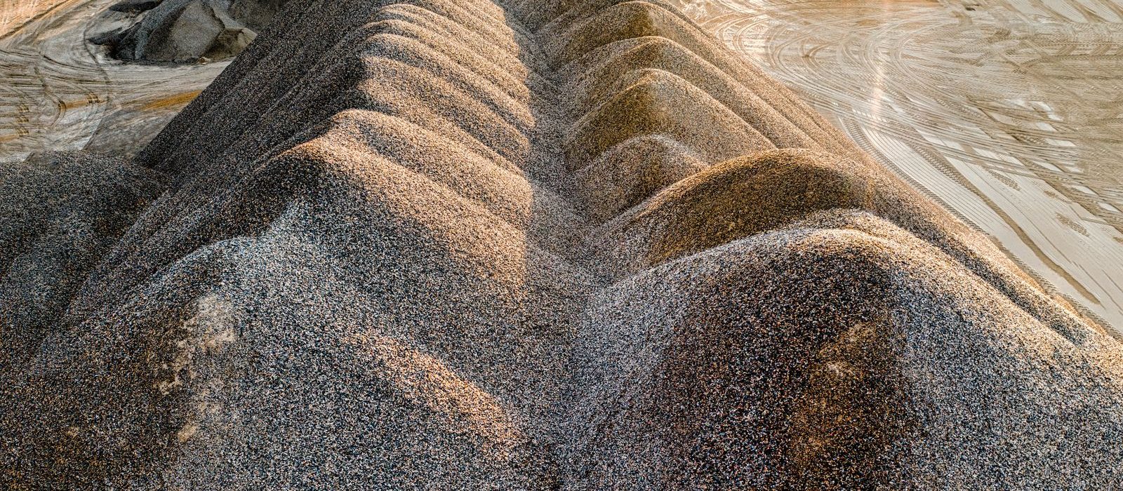 Long windrows of sand and gravel at a pit in low evening light